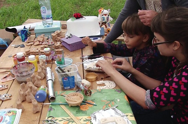Bezoekers en kunstenaars werken aan zandbeeldhouwerijen in het Loopuytpark van Julianadorp